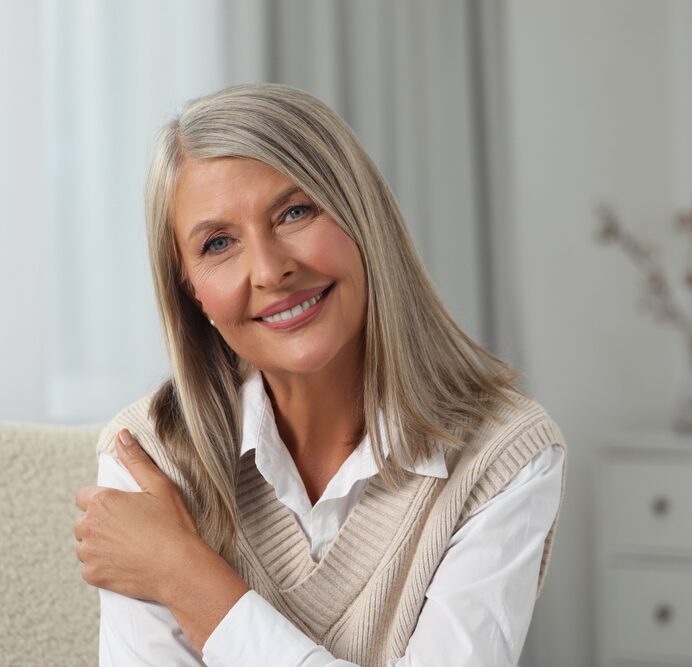 Smiling mature woman indoors, showing confidence and comfort achieved through Dental Crowns at West Kerr Dental