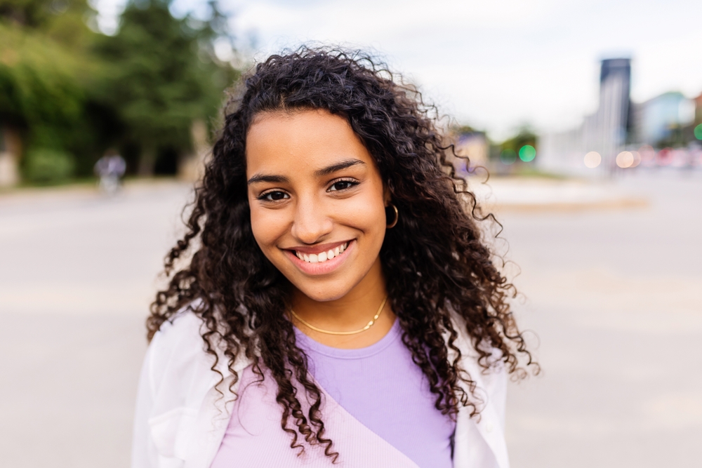 Smiling young woman outdoors with radiant teeth, representing confidence and wellness through Dental Services at West Kerr Dental