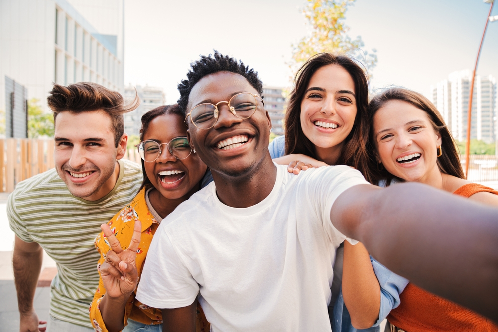 Group of friends smiling brightly outdoors, highlighting Invisalign treatment at West Kerr Dental for confidence
