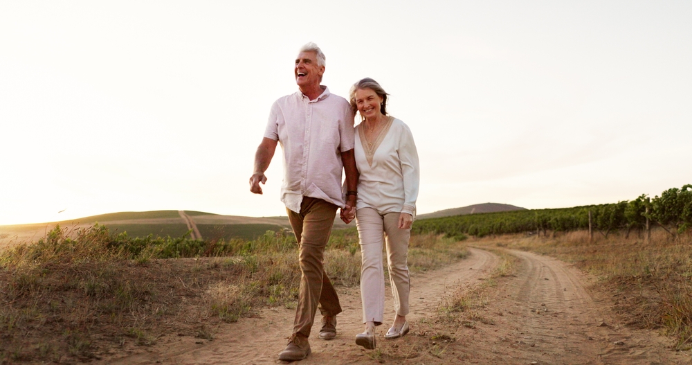 Smiling senior couple walking outdoors at sunset, showcasing confidence restored with Dental Crowns at West Kerr Dental